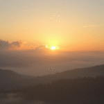 Peaceful sunrise over misty mountains with soft golden light filtering through clouds symbolizing hope and clarity no text no words no letters