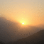 Peaceful sunrise through misty mountains with soft golden light representing hope and clarity, serene landscape, no text no words no letters