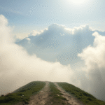 Serene mountain path disappearing into soft misty clouds, gentle sunlight filtering through, peaceful journey concept, no text no words no letters