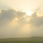 Soft misty morning landscape with gentle sunlight breaking through clouds symbolizing clarity emerging from uncertainty no text no words no letters