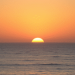 Gentle sunrise over calm ocean horizon with soft golden light representing hope and new beginnings no text no words no letters