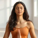 Person in peaceful meditation pose in modern minimalist room with soft natural light filtering through windows, showing calm facial expression and relaxed shoulders, photorealistic