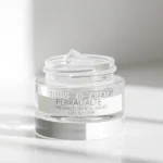 Close-up of a transparent gel-like therapeutic product in a minimalist glass container on a clean white surface, with soft natural lighting highlighting the product's clarity and professional presentation, modern dermatology aesthetic