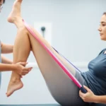 Physical therapist demonstrating hip strengthening exercise with resistance band on female patient in bright clinical setting, professional medical environment, detailed form correction