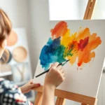 Person painting with watercolors on canvas in bright studio, colorful abstract brushstrokes, natural light from window, hands creating art, peaceful expression